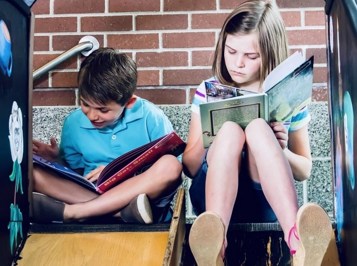 Dziewczynka i chłopiec siedząc czytają książki
