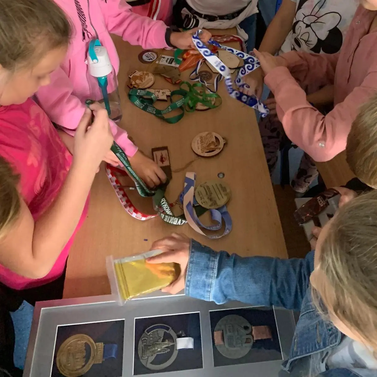 Dzieci oglądają medale leżące na stole.