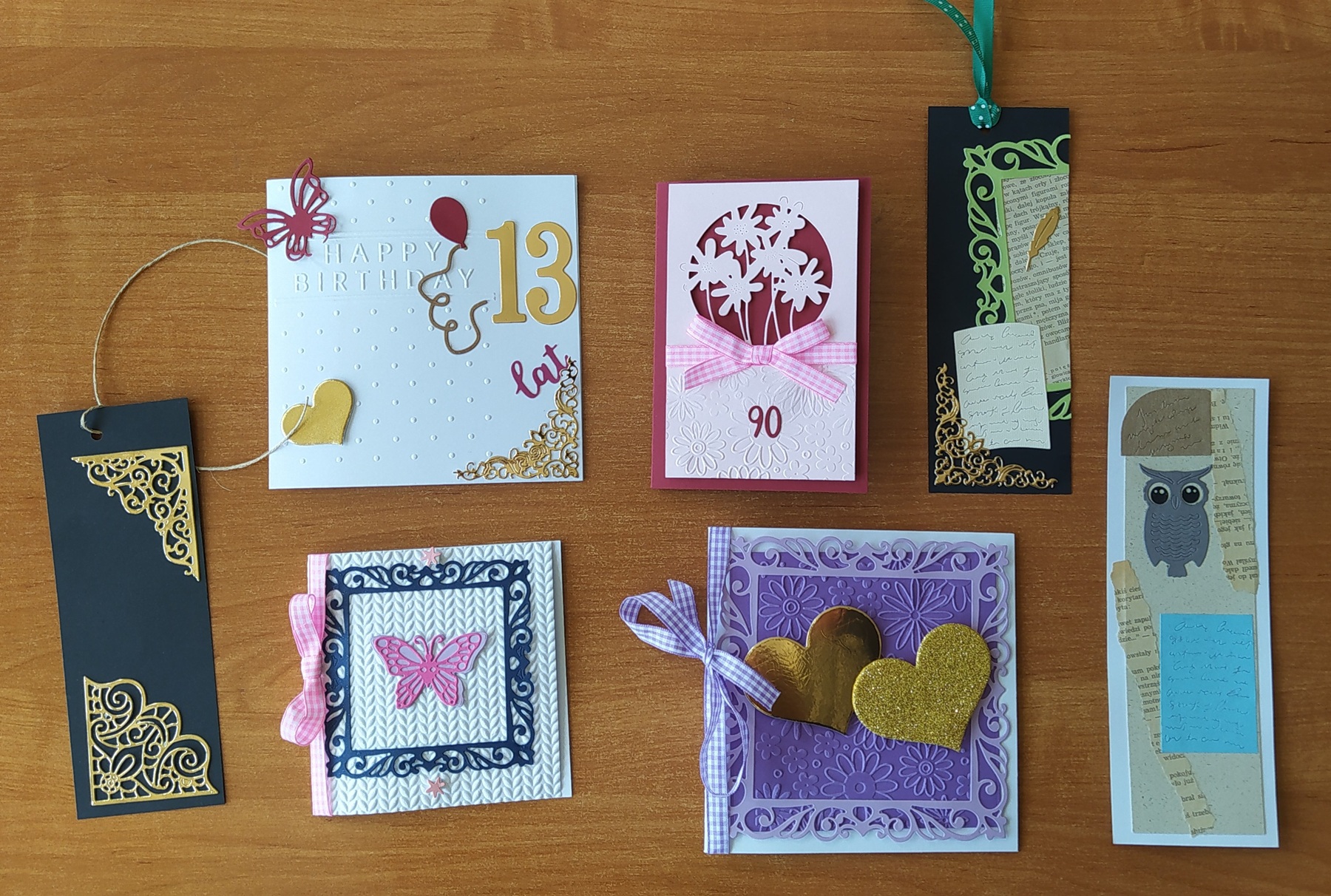 Na brązowym stole leżą kolorowe karty okolicznościowe i zakładki.