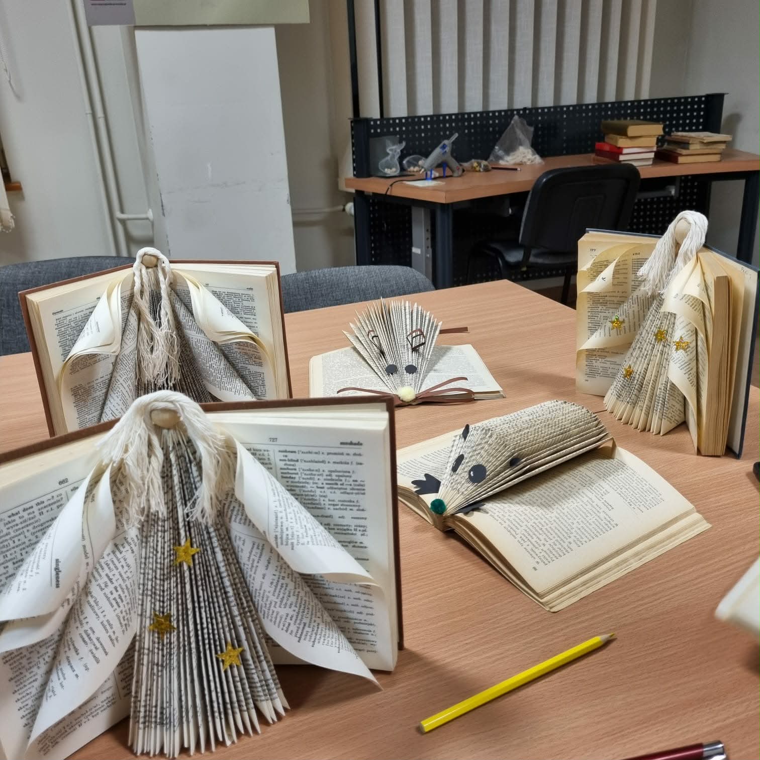 Na stoliku stoją prace wykonane ze starych książek Anioły, mysz, jeż.