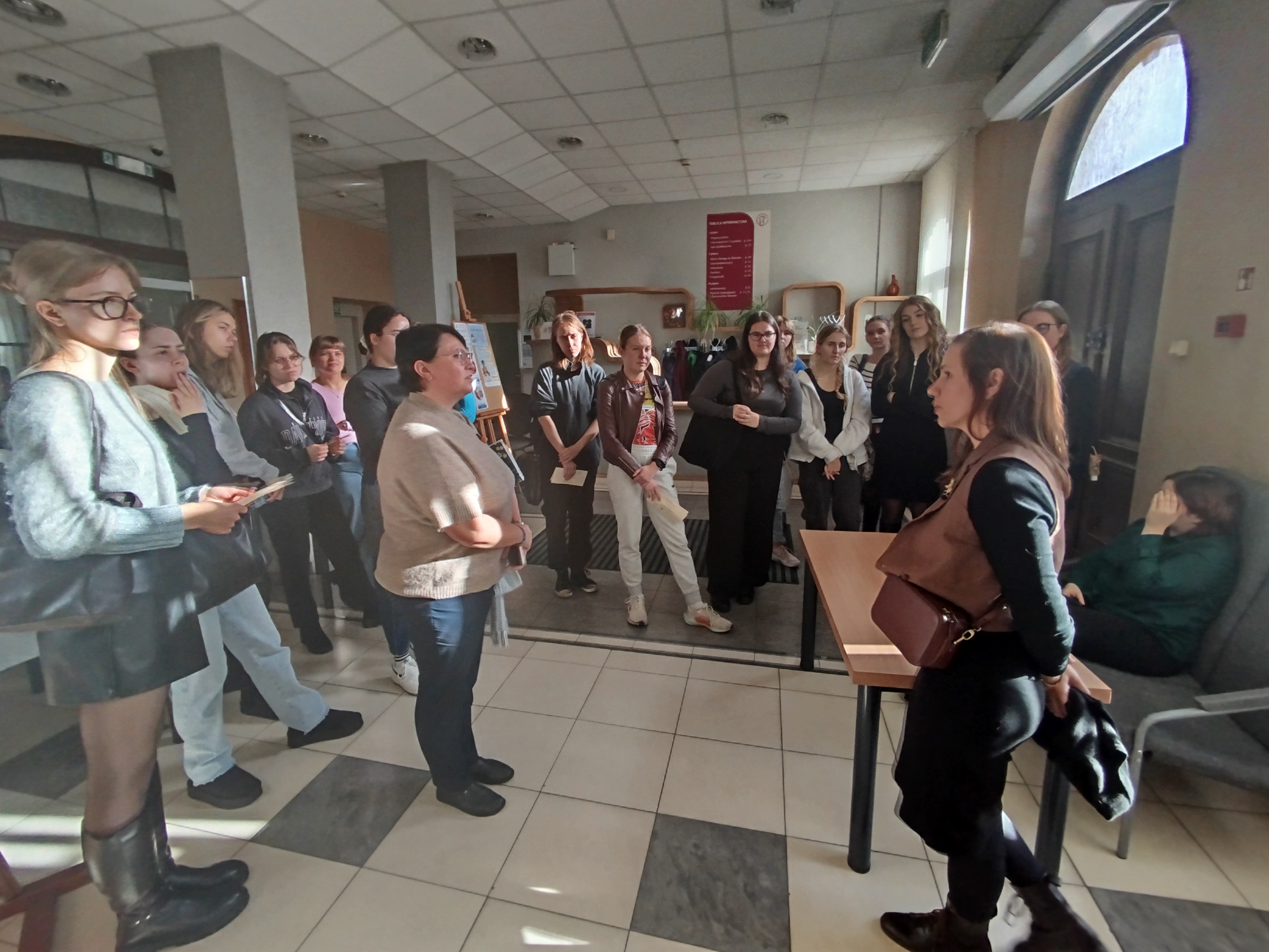 Grupa ludzi stoi w sali wystawowej Biblioteki Pedagogicznej w Toruniu.
