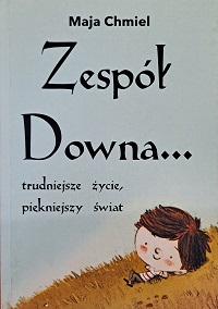 Okładka książki pt.: Zespół Downa... trudniejsze życie, piękniejszy świat. Na okładce, na białym tle widoczny fragment żółtego pagórka, na którym leży chłopiec z brązową czupryną.